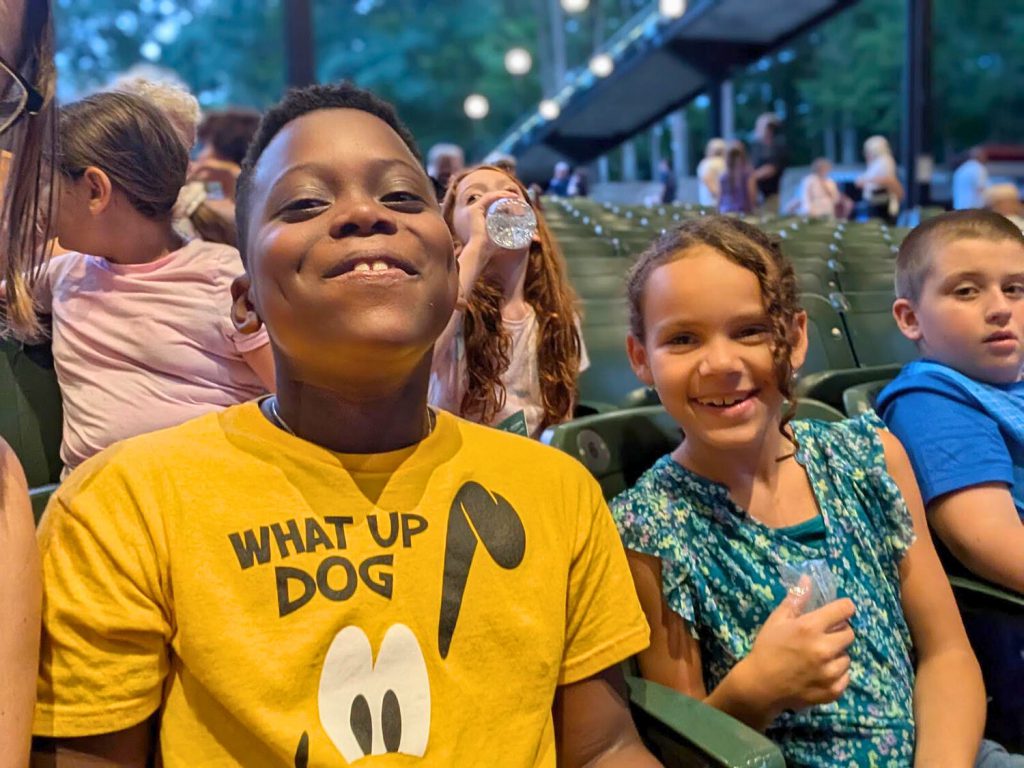 Two elementary students smiling for a photo as they sit in the amphitheater's audience.