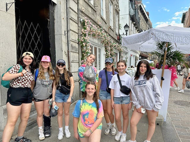 Group of female middle school students standing for a group photo with the streets of Montreal behind them.