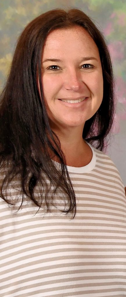 Woman smiling wearing a tan and white tee shirt. 